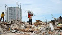Seorang pria membawa sisa-sisa besi dari reruntuhan bangunan yang dirobohkan di kawasan Pasar Ikan, Penjaringan, Jakarta, Selasa (12/4). Selain warga, sejumlah pemulung besi berhambur untuk menjarah besi dari bekas bangunan (Liputan6.com/Yoppy Renato)