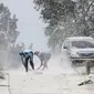 Warga mengenakan masker membersihkan jalan yang tertutup abu vulkanik Gunung Sinabung di Karo, Sumatra Utara (20/2). Gunung Sinabung meletus kembali tanggal 19 Februari, yang mengeluarkan asap tebal setinggi 5.000 meter. (AFP Photo/Kadri Boy Tarigan)