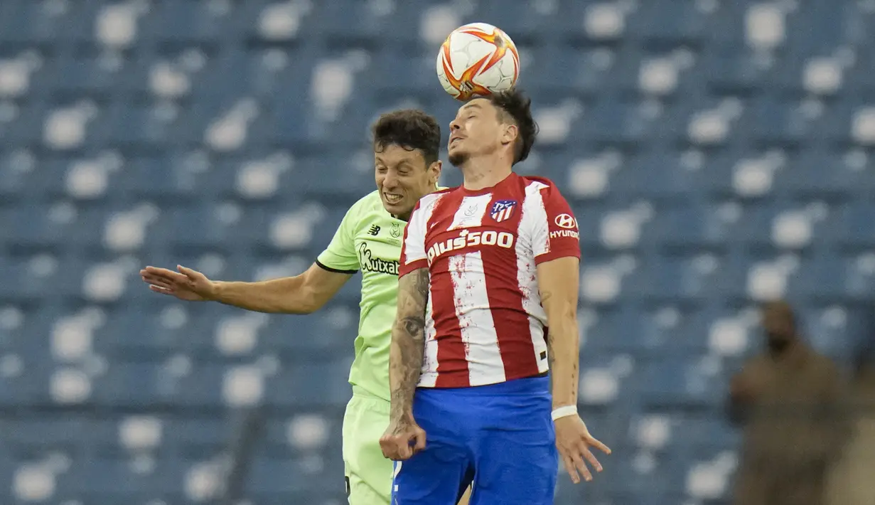 Gelandang Athletic Bilbao Mikel Vesga dan bek Atletico Madrid Jose Gimenez melompat saat berebut bola pada semifinal Piala Super Spanyol 2022 di Stadion Raja Fahd, Arab Saudi, Jumat (14/1/2022) dinihari WIB. Athletic Bilbao membuat kejutan dengan mendepak Atletico Madrid 2-1. (AP Photo/Hassan Ammar)