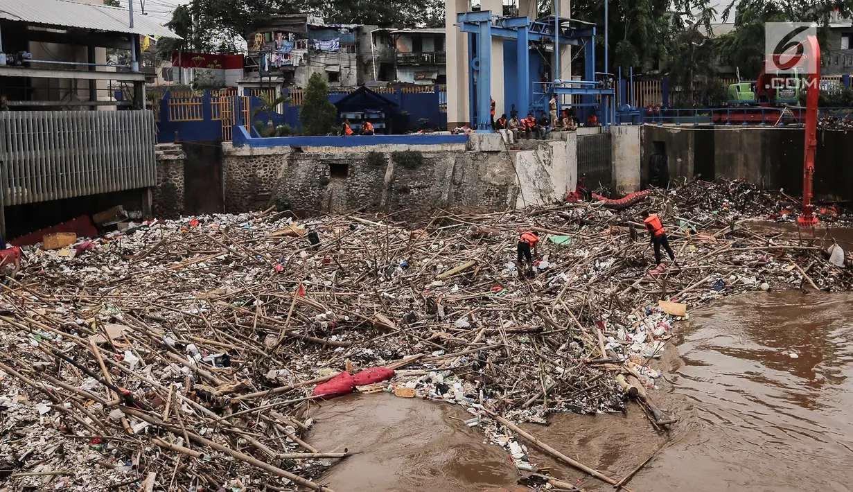 Sebuah eskavator dibantu petugas kebersihan mengangkat tumpukan sampah di Pintu Air Manggarai, Jakarta, Senin (12/11). Sejumlah petugas mengenakan pelampung oranye di atas tumpukan sampah yang berada di sungai. (Liputan6.com/Fery Pradolo)