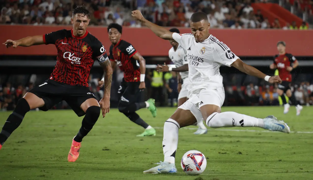 Pemain Real Madrid, Kylian Mbappe (kanan) berusaha mencetak gol ke gawang Real Mallorca pada laga Liga Spanyol 2024/2025 di Mallorca Son Moix stadium, Spanyol, Senin (19/08/2024) dini hari WIB. (AP Photo/Francisco Ubilla)