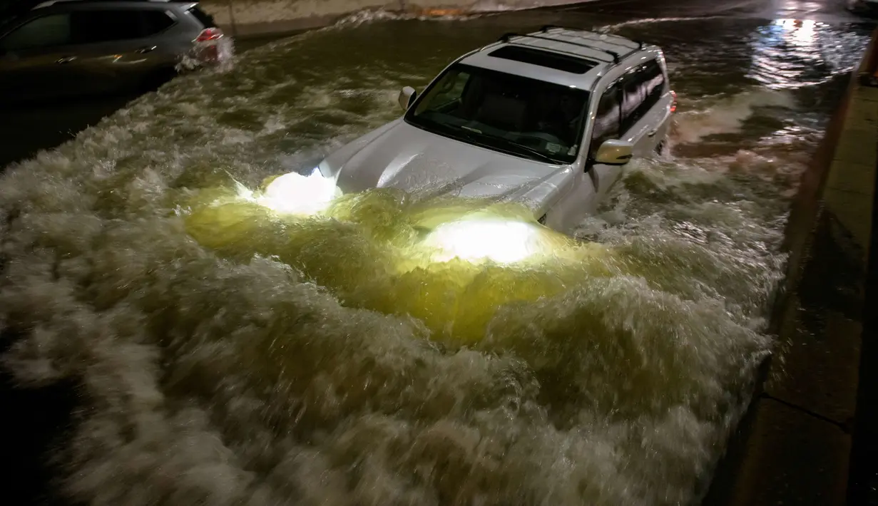Sebuah mobil berusaha menerjang banjir yang merendam jalanan di Brooklyn, New York, Amerika Serikat, Kamis (2/9/2021). Pemerintah setempat sampai mengumumkan status darurat banjir bandang, suatu peringatan yang jarang sekali dikeluarkan. (AFP/Ed Jones)