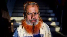 Dalam gambar yang diambil pada 24 Desember 2018, pedagang kaki lima bernama Amir Hossain dengan janggut oranye di Dhaka. Para pria tua yang ingin tetap merasa muda mewarnai janggut dengan henna, pewarna tradisional yang sudah terkenal di Bangladesh beberapa dekade lamanya. (MUNIR UZ ZAMAN / AFP)