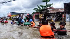 Para relawan membantu warga melewati derasnya banjir di Makassar pada 12 Februari 2025. (DAENG MANSUR/AFP)
