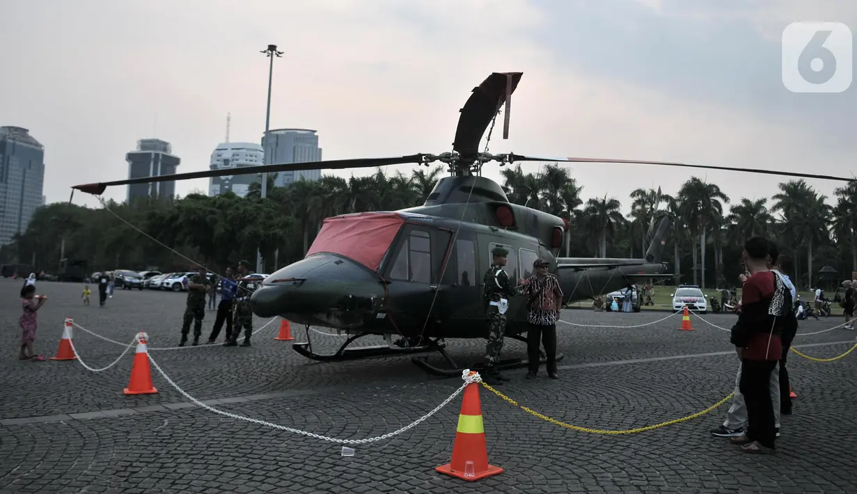 Warga berfoto dengan helikopter TNI yang terparkir di kawasan Monas, Jakarta, Rabu (16/10/2019). Kehadiran empat helikopter TNI/Polri yang akan digunakan dalam apel pengamanan pelantikan presiden dan wakil presiden tersebut menarik perhatian pengunjung Monas. (merdeka.com/Iqbal Nugroho)