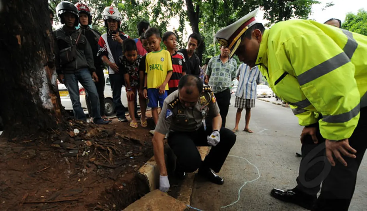Seorang anggota polisi menandai salah satu lokasi kejadian kecelakaan maut di ruas Jalan Sultan Iskandar Muda, Pondok Indah, Jakarta, Kamis (22/1/2015). (Liputan6.com/Helmi Fithriansyah)