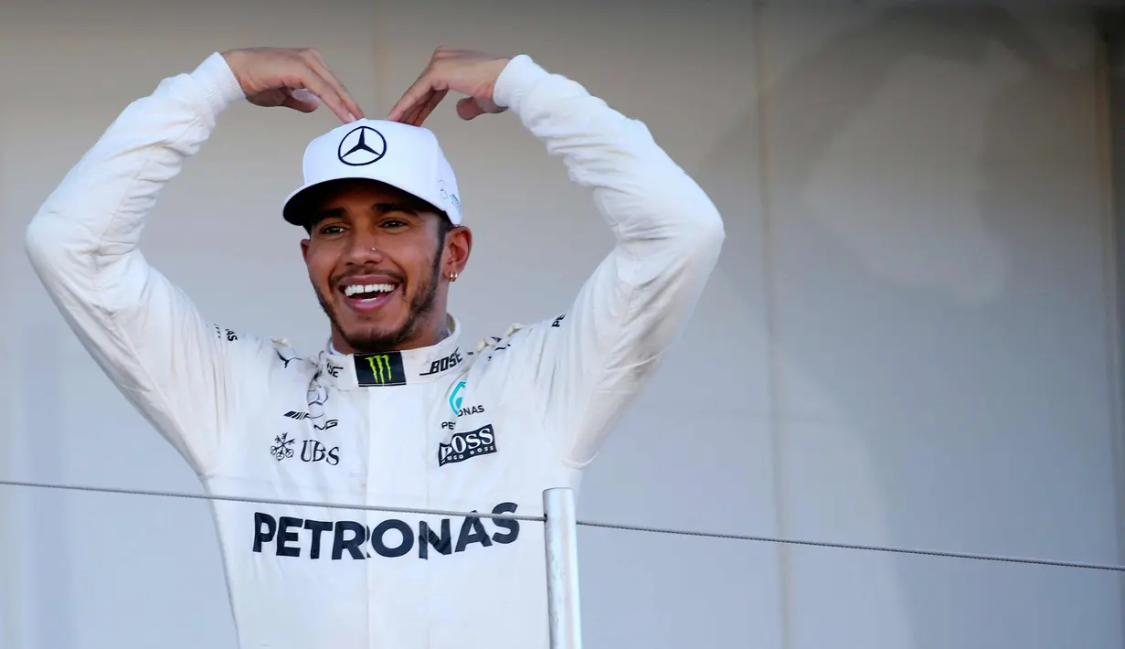 Pembalap F1 dari tim Mercedes Lewis Hamilton dari Inggris berpose di atas podium usai memenangkan GP F1 Jepang di Sirkuit Suzuka, Jepang, (8/10). Dengan kemenangan ini, Hamilton menjauh dari Sebastian Vettel di klasemen F1. (AP Photo / Toru Takahashi)