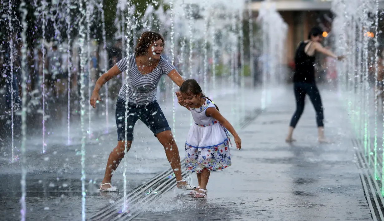 Warga bermain diantara air mancur saat menikmati musim panas di taman Gorky, Moskow, Rusia, Minggu (9/8/2015). (REUTERS/Sergei Karpukhin)