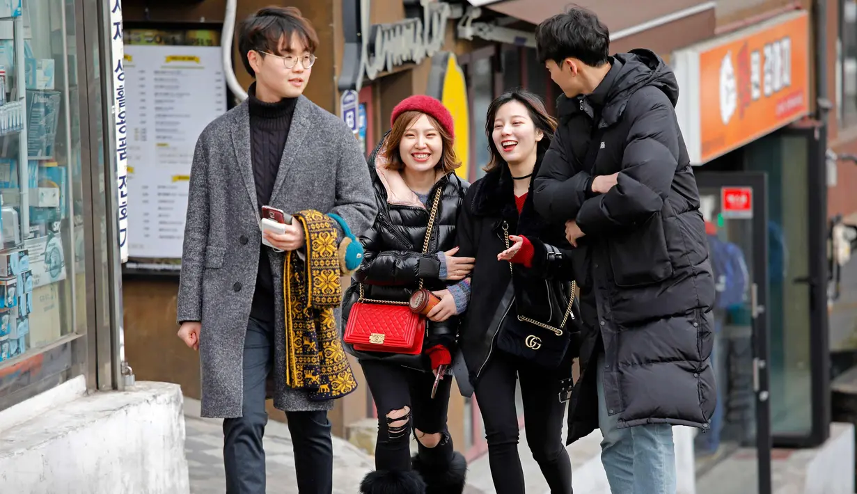 Sejumlah remaja berbincand sambil berjalan di sepanjang jalan di Seoul, Korea Selatan (19/2). (AFP Photo/David Gannon)