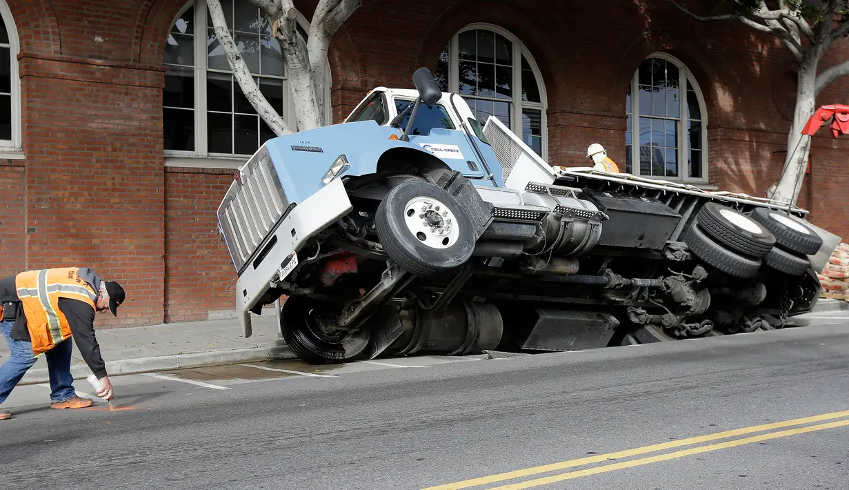 Petugas membuat tanda di sekitar lokasi truk yang terjebak di sebuah saluran pembuangan di San Francisco, AS, Jumat (5/5). (AP Photo / Jeff Chiu)
