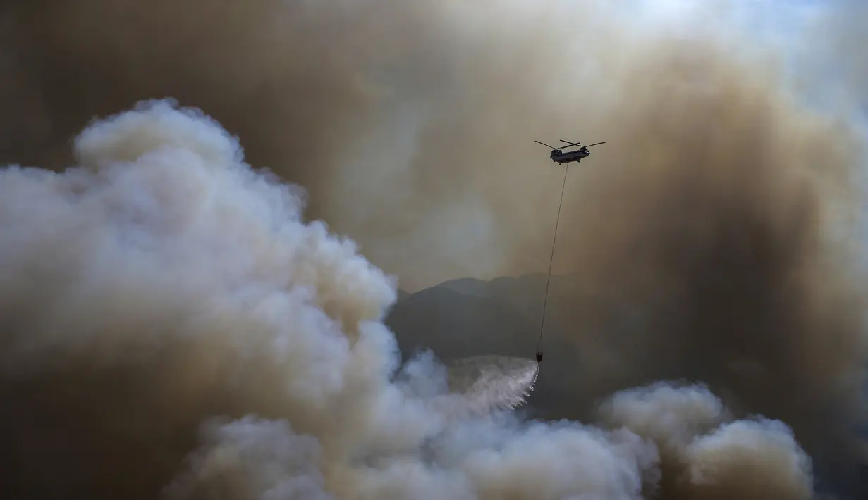 Sebuah helikopter berpartisipasi dalam operasi pemadaman kebakaran hutan di Koycegiz, Mugla, Turki, Senin (9/8/2021). Kebakaran hutan yang terjadi di tengah gelombang panas ganas telah berkobar selama berhari-hari di lebih dari setengah provinsi Turki. (AP Photo/Emre Tazegul)