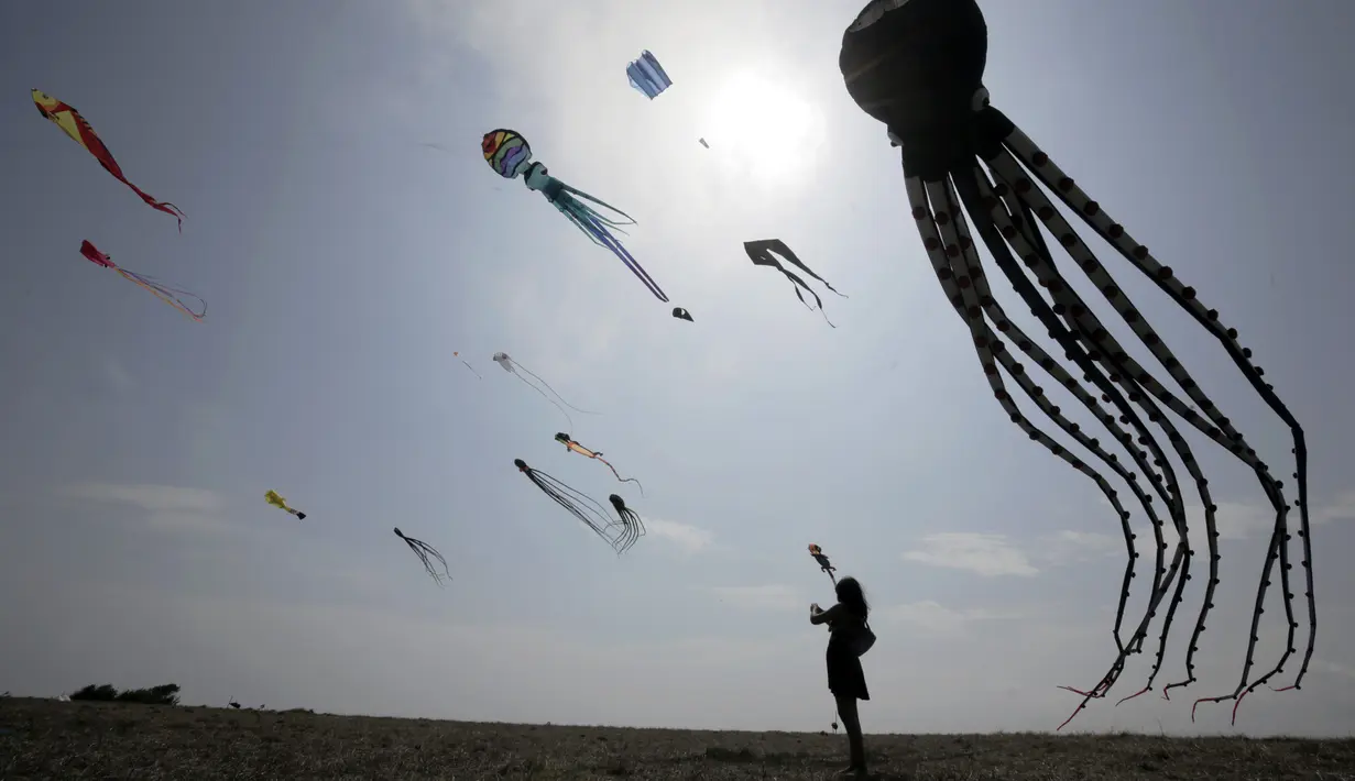 Seorang wanita melihat layang-layang dalam Varvara Kite Fest di Desa Varvara, pesisir Laut Hitam, Bulgaria, Jumat (27/8/2021). Penyelenggara Varvara Kite Fest Andrey Kulev mengatakan bahwa menerbangkan layang-layang seperti melepaskan semua masalah Anda di langit. (AP Photo/Valentina Petrova)