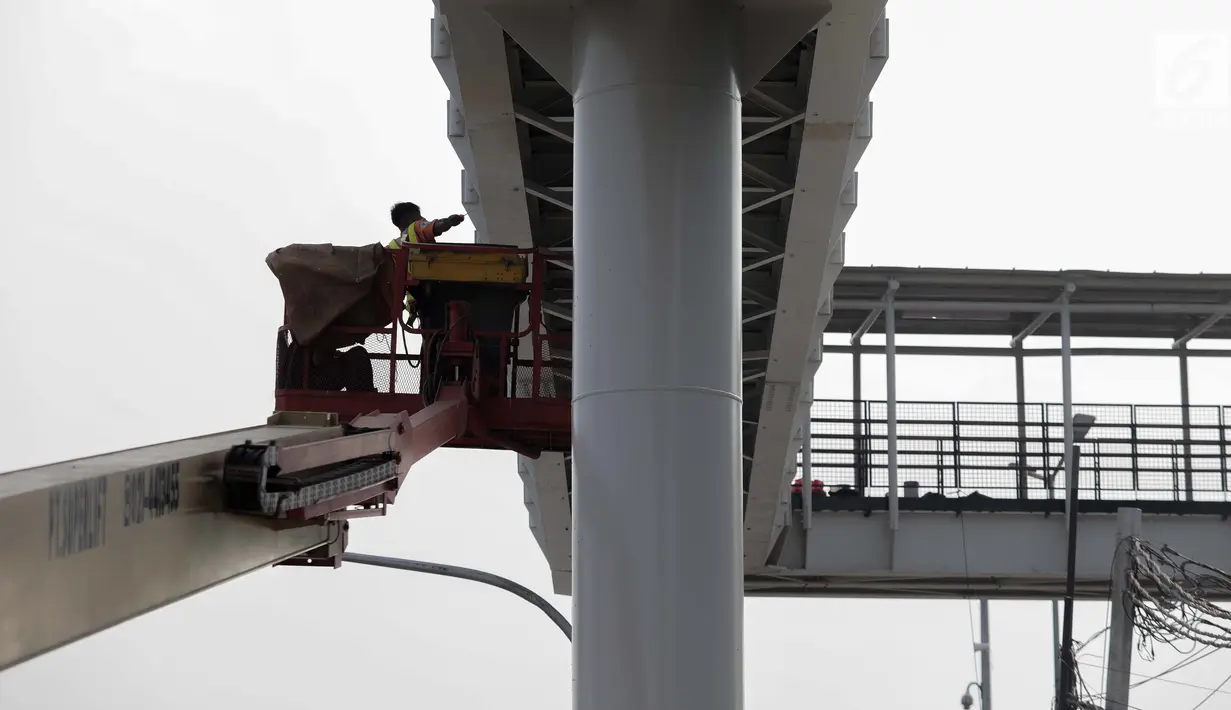 Pekerja menyelesaikan pembangun jembatan Skybridge di Ramangun, Jakarta, Kamis (4/7/2019). Pembangunan Skybridge sudah 98 persen rampung, yang nantinya akan menghubungkan Stasiun Kereta LRT Velodrome dengan halte busway Pemuda Rawamangun akan rampung akhir bulan ini. (Liputan6.com/Faizal Fanani)