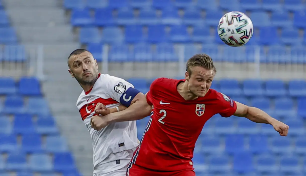 Penyerang Turki, Burak Yilmaz berebut bola dengan bek Norwegia, Stian Gregersen pada lanjutan Kualifikasi Piala Dunia 2022 zona Eropa Grup G di stadion La Rosaleda di Malaga, Spanyol, Minggu (28/3/2021). Turki menang telak atas Norwegia 3-0. (AP Photo/Fermin Rodriguez)