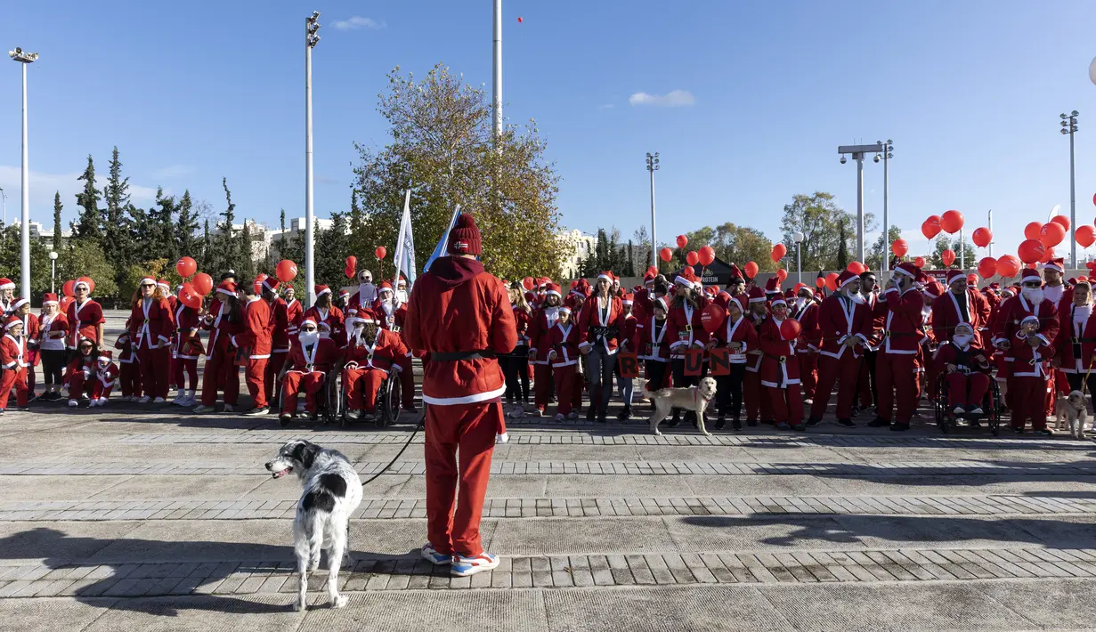 Orang-orang yang mengenakan kostum Sinterklas menunggu di garis start Athena Santa Run, di Athena, Yunani, Minggu (12/12/2021). Ratusan orang berpartisipasi mengikuti lomba lari untuk acara amal di area sekitar kompleks Stadion Olimpiade Athena. (AP Photo/Yorgos Karahalis)