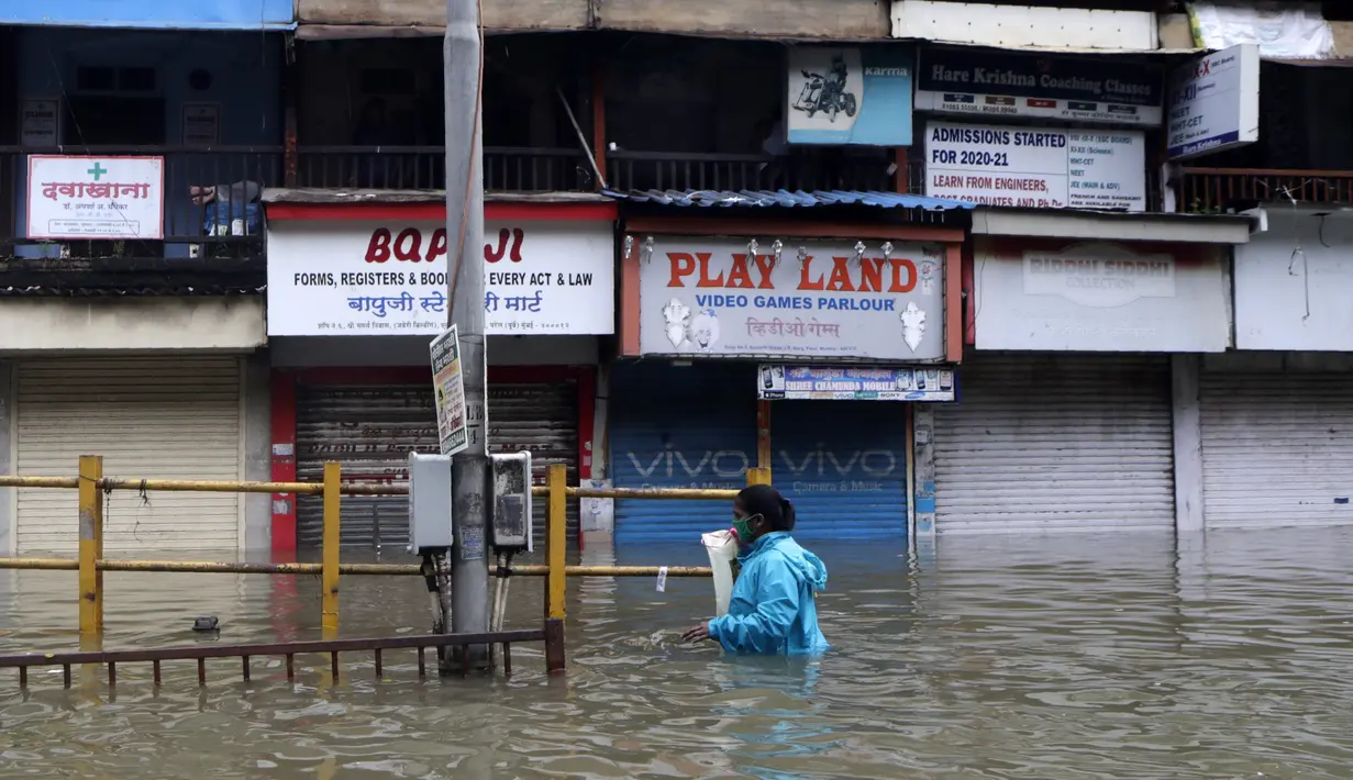 Seorang wanita berjalan melewati jalan yang tergenang air setelah hujan lebat di Mumbai, India, Rabu (23/9/2020). Musim hujan di India berlangsung dari Juni hingga September. (AP Photo/Rajanish Kakade)