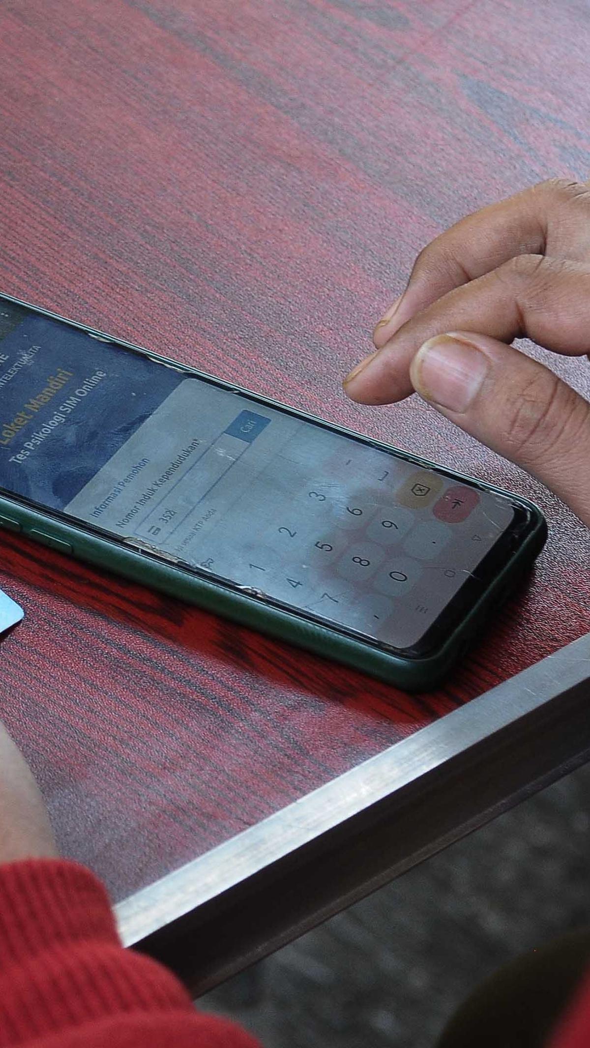 Pemohon perpanjangan SIM mencoba melakukan pendaftaraan secara Online di Gerai Satpas Jakarta Timur untuk mengikuti tes Psikologi.