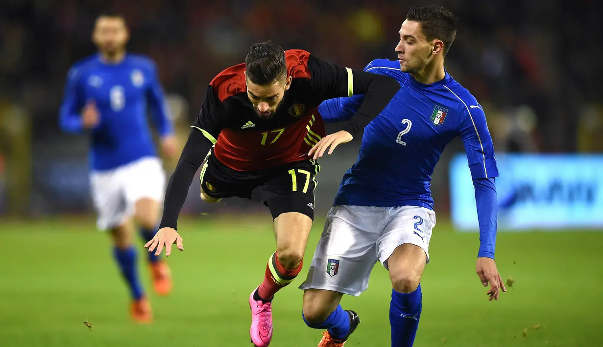 Pemain Belgia, Yannick Carrasco terjatuh saat berebut bola dengan pemain Italia, Mattia De Sciglio pada laga persahabatan di Stadion King Baudoin, Belgia, Sabtu (13/11/2015). (AFP Photo/Emmanuel Dunand)