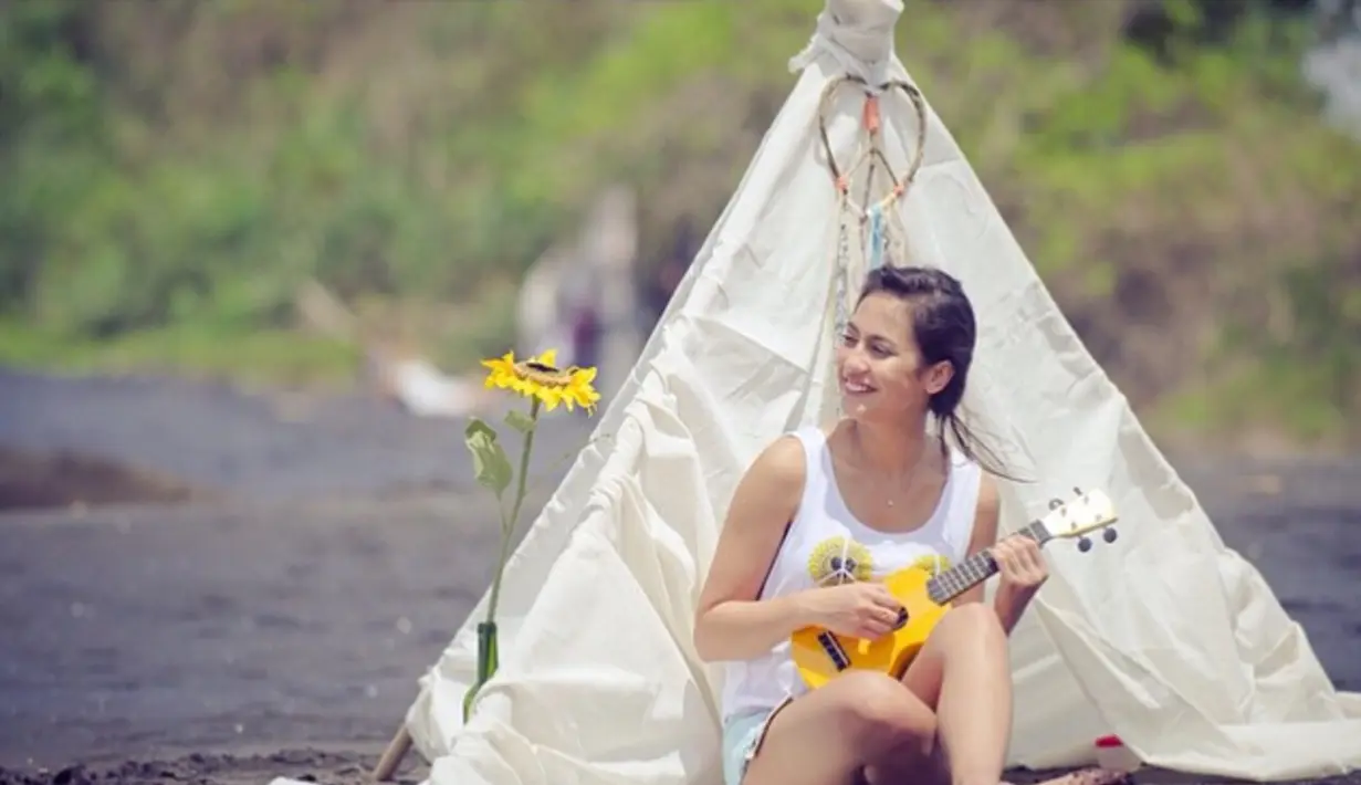 Ada-ada saja gaya Pevita Pearce saat bersantai di pantai. Lihat di belakangnya ada tenda fantasi. Sambil memainkan ukulele ia berdendang. (instagram @pevpearce)
