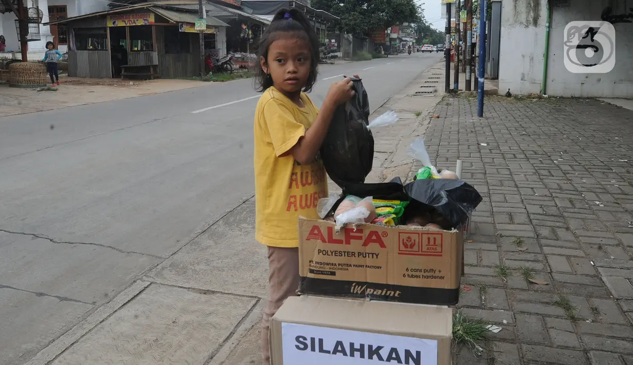 Seorang anak mengambil mi instan dan telur gratis di Jalan Raya Cibubur-Bojong Kulur, Bogor, Kamis (9/4/2020). Di beberapa pinggir jalan Kawasan Jabotabek saat ini banyak aksi solidaritas oleh warga dengan menyediakan bahan makanan gratis di tengah pandemi virus corona. (merdeka.com/Arie Basuki)