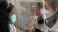 Petugas kesehatan menunjukkan jarum suntik kosong usai menyuntik seorang wanita dengan vaksin COVID-19 pada hari pertama vaksinasi nasional di sebuah sekolah di Kota Quezon, Filipina, Senin (29/11/2021). Kemunculan COVID-19 varian Omicron telah memicu alarm baru di Filipina. (AP Photo/Aaron Favila)