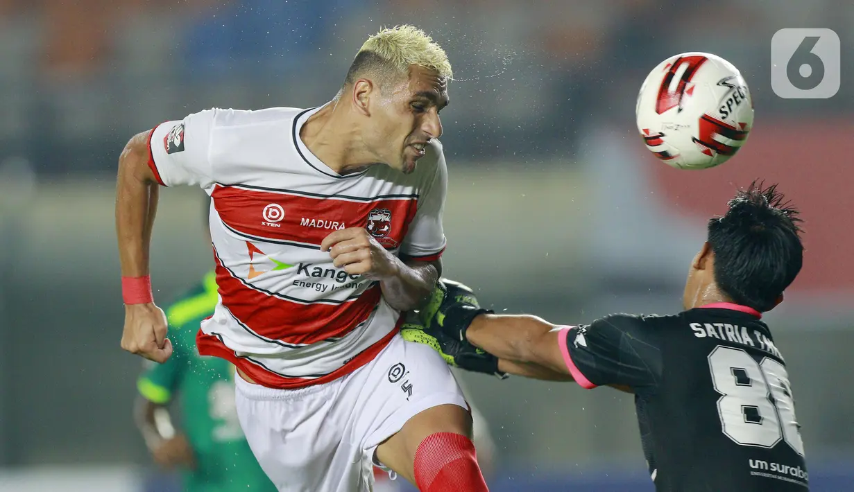 Bek Madura United, Jaimerson (kiri) duel udara dengan kiper Persebaya Surabaya, Satria Tama, pada laga Piala Menpora 2021 di Stadion Si Jalak Harupat, Bandung, Minggu (28/3/2021). Persebaya Surabaya menang 2-1. (Bola.com/M Iqbal Ichsan)