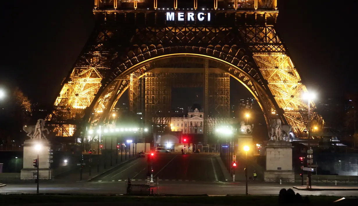 Kata "Merci atau terima kasih terpampang di Menara Eiffel, Paris, Jumat (27/3/2020). Menara Eiffel menyala untuk menampilkan pesan dukungan dan terima kasih kepada tenaga kesehatan di Prancis yang berada di garda depan memerangi pandemi COVID-19.  (AP/Thibault Camus)