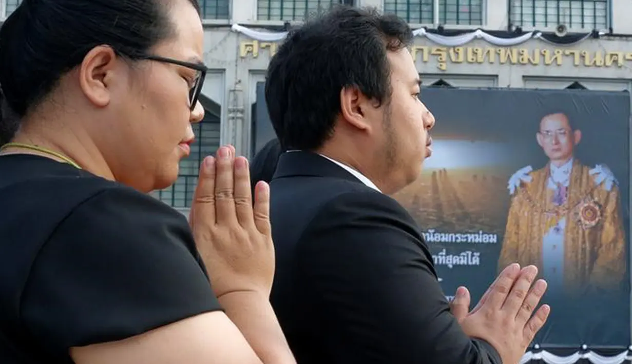Sejumlah warga berdoa di dekat Grand Palace di Bangkok, Thailand, Rabu (19/10). Untuk menghormati Raja Bhumibol Adulyadej, Grand Palace dipasangi gambarnya. (REUTERS / Chaiwat Subprasom)