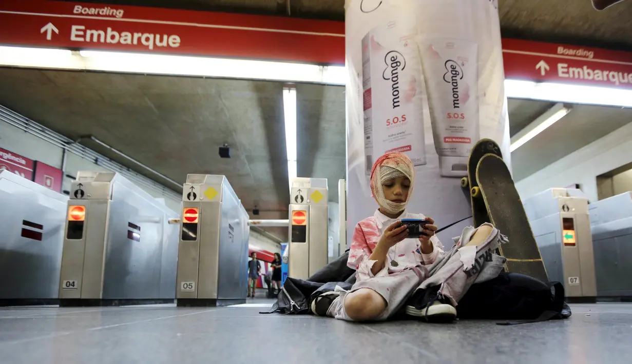 Seorang anak bermain ponsel di stasiun metro sebelum menghadiri parade "Zombie Walk" di Sao Paulo, Brasil, Senin (2/11/2015). (REUTERS / Paulo Whitaker)