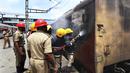 Petugas kereta api memadamkan api di gerbong kereta api di stasiun kereta api Secundrabad di Hyderabad, India, Jumat (17/6/2022). Hampir 500 pengunjuk rasa jauh melebihi jumlah polisi saat mereka mengamuk selama lebih dari satu jam di stasiun kereta api Secundrabad di India selatan. (AP Photo/Mahesh Kumar A)