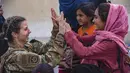 Seorang Penerbang AS dengan Satuan Tugas Gabungan-Respons Krisis melakukan tos dengan seorang anak setelah membantu menyatukan kembali keluarga mereka di Bandara Internasional Hamid Karzai di Kabul, Afghanistan, Jumat (20/8/2021).  (Cpl. Davis Harris/U.S. Marine Corps via AP)