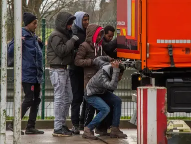 Sejumlah imigran terlihat tengah membuka pintu truk di A25 autoroute, Steenvoorde, Prancis (27/2). Para imigran ini nekat sembunyi saat menghindari kejaran petugas imigrasi. (AFP Photo / Philippe Huguen)