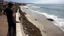 Warga melihat bangkai paus kelabu di Pantai Maria Martha, Baja California, Meksiko (12/9). Bangkai paus dengan kondisi perut tersobek jadi perhatian warga sekitar di lokasi tersebut. (AFP Photo/Guillermo Arias)