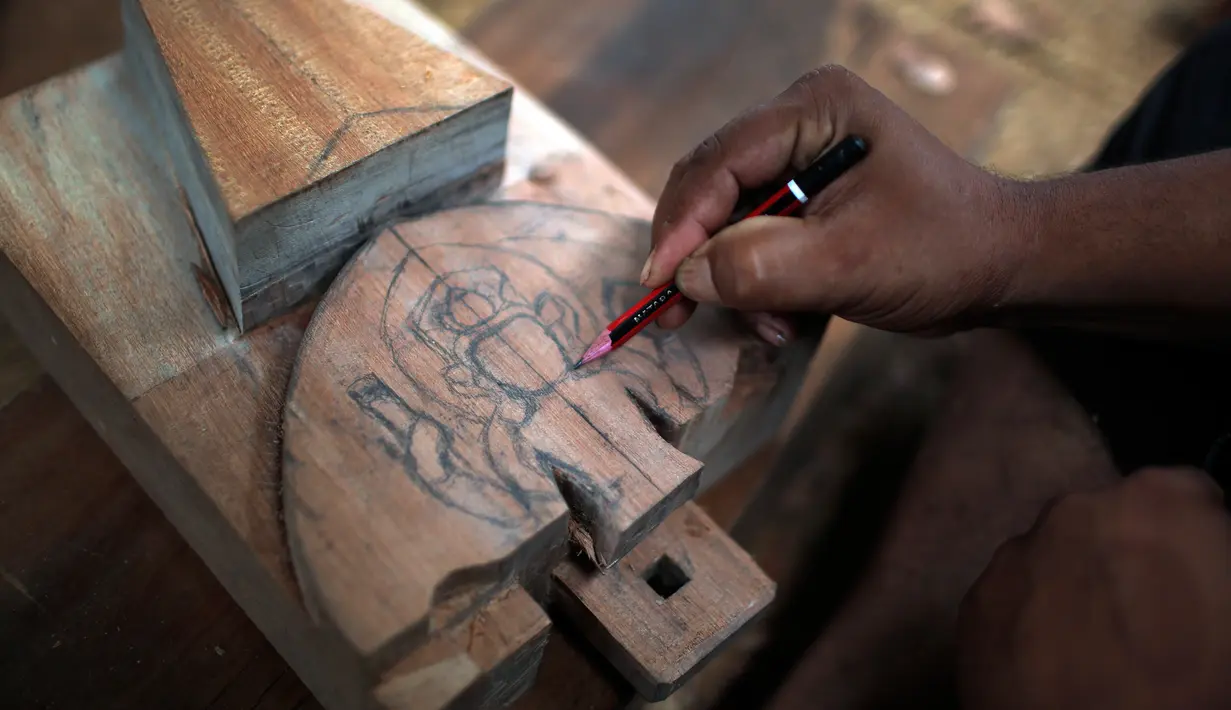 Seorang pengrajin kayu dari komunitas etnis Newar membuat sketsa diatas kayu sebelum diukir di Lalitput, Nepal (19/7). Komuitas pengrajin kayu ini memulai aktivitas sosialnya sejak dua tahun lalu. (AP Photo/Niranjan Shrestha)