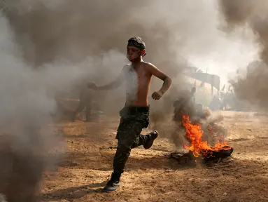 Seorang anak Palestina berlari saat mengambil bagian dalam latihan militer di sebuah kamp musim panas yang diselenggarakan oleh Islamic Jihad Movement di Khan Younis di Jalur Gaza selatan (13/7). (REUTERS/Ibraheem Abu Mustafa)