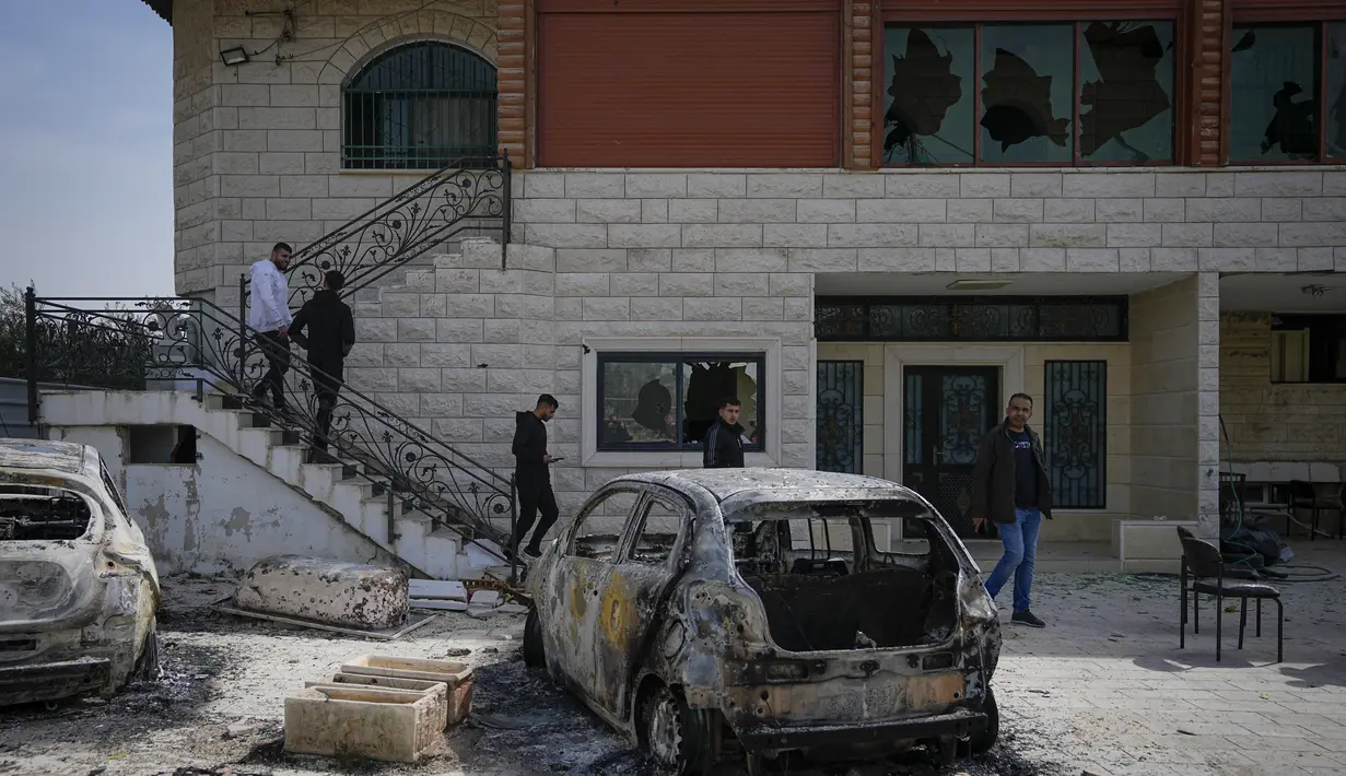 Warga Palestina memeriksa rumah yang rusak dan mobil yang hangus di kota Hawara, dekat kota Nablus di Tepi Barat, Senin, 27 Februari 2023. Puluhan pemukim Israel mengamuk dengan kekerasan di Tepi Barat utara, membakar  mobil dan rumah-rumah setelah dua pemukim dibunuh oleh seorang pria bersenjata Palestina. (AP Photo/Ohad Zwigenberg)