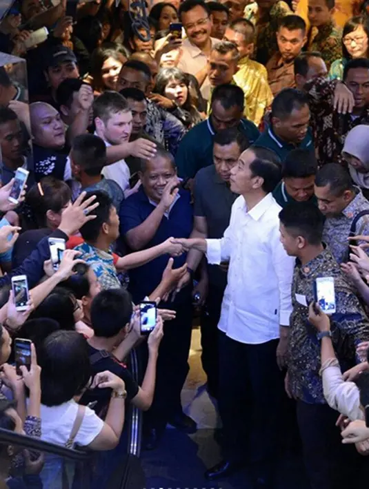 Berjalan dengan mengenakan kemeja putih lengan panjang dan celana hitam. Kedatangannya tentu membuat heboh pengunjung yang hadir dan para penjaga toko yang ada. Seperti biasa, masyarkat berebut untuk bersalaman. (Instagram/jokowipedia)