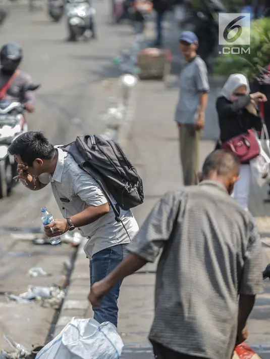 Seorang pria mencuci muka dengan air untuk menghindari sisa gas air mata pasca bentrok massa dengan aparat di Palmerah, Jakarta, Kamis (26/9/2019). Banyak masyarakat yang melintas dan warga sekitar perih pada mata hingga bersin akibat sisa gas air mata. (Liputan6.com/Faizal Fanani)