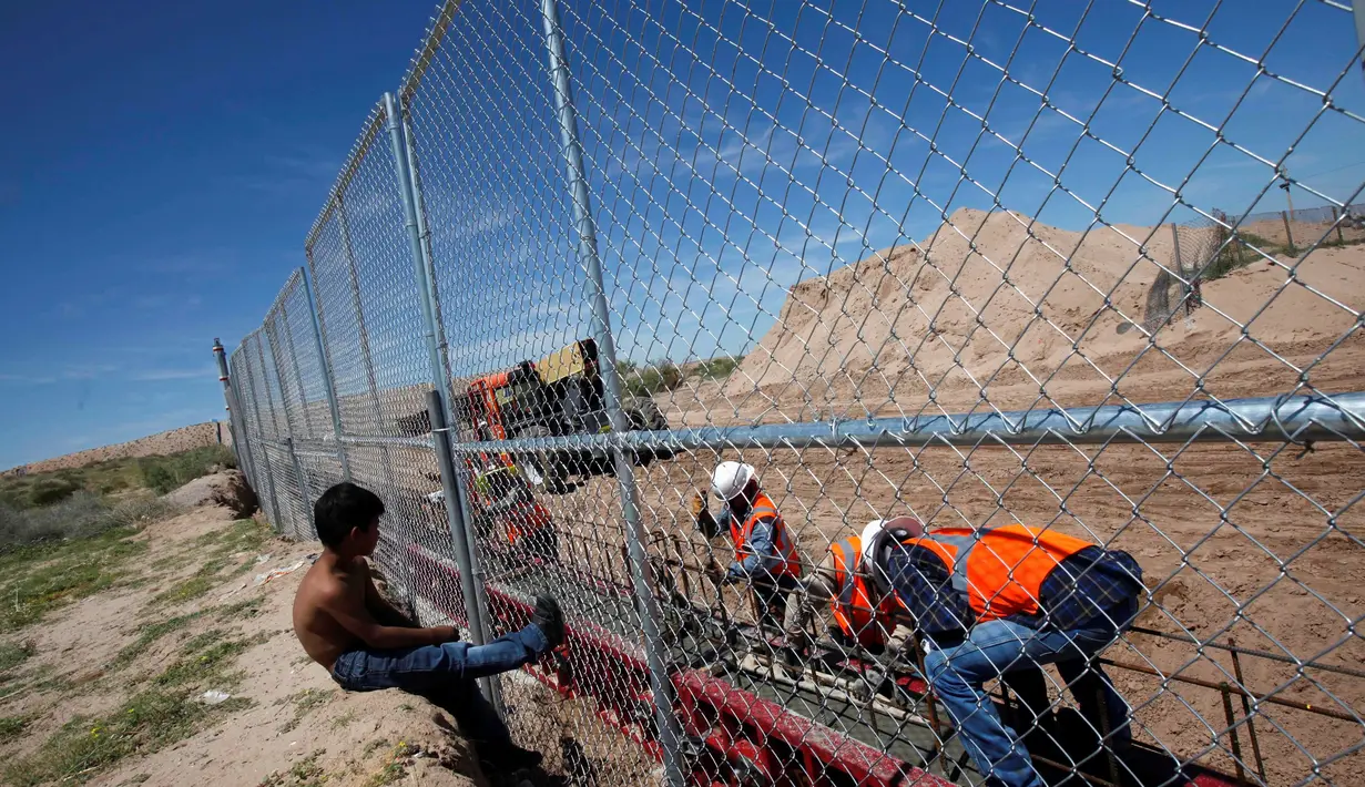 Seorang anak melihat pekerja dari Amerika Serikat saat membangun dinding perbatasan AS-Meksiko di Sunland Park, AS (09/9). Dinding perbatasan dibangun karena diduga sebagai pintu masuk imigran ilegal asal Mexico ke wilayah AS.(REUTERS/Jose Luis Gonzalez)