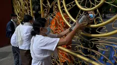 Warga memberikan makanan dan sedekah kepada biksu Buddha saat Festival Pchum Ben (Festival Kematian) di luar pagoda di Phnom Penh, Kamboja, 24 September 2021. Pihak berwenang menghentikan perayaan Festival Kematian karena pandemi COVID-19. (TANG CHHIN Sothy/AFP)
