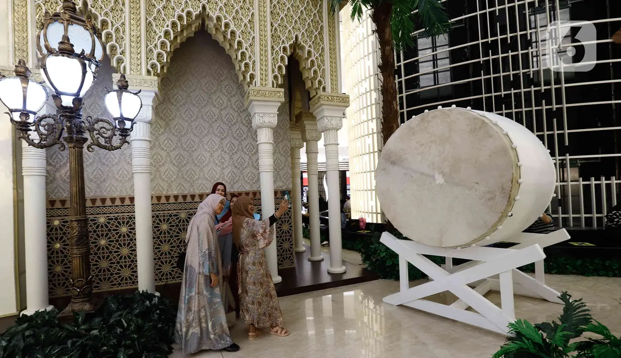 Pengunjung berswafoto saat melihat-lihat instalasi Istana Alhambra di Mal Senayan City, Jakarta Pusat, Kamis (15/4/2022). Instalasi megah setinggi 14 meter itu merupakan perwujudan dari tema The Divine Ramadan yang dibuat untuk menyemarakkan bulan puasa. (Liputan6.com/Herman Zakharia)