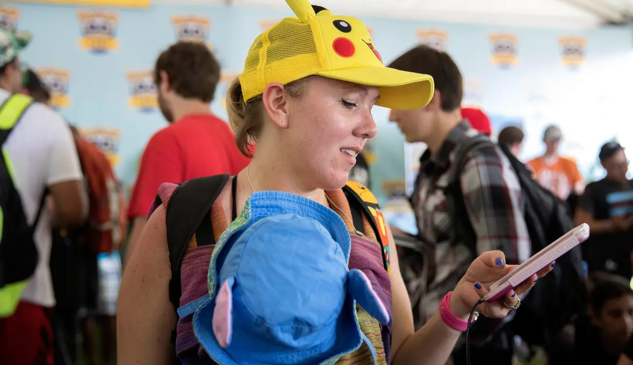 Peserta asal Miami menggendong anaknya sambil berusaha mendapatkan pokemon dalam Festival Pokemon Go, di Giant Park, Chicago, Sabtu (22/7). Festival ini dihadiri oleh penggemar game fenomenal Pokemon Go dari berbagai kota. (AP/Erin Hooley)