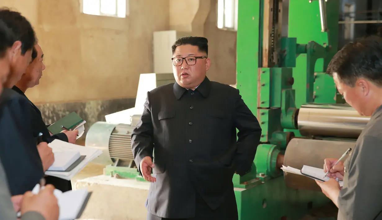Pemimpin Korea Utara, Kim Jong-un berbincang saat meninjau Sinuiju Chemical Fiber Mill di Sinuiju, Korea Utara (2/7). (AFP Photo/KCNA Via KNS)