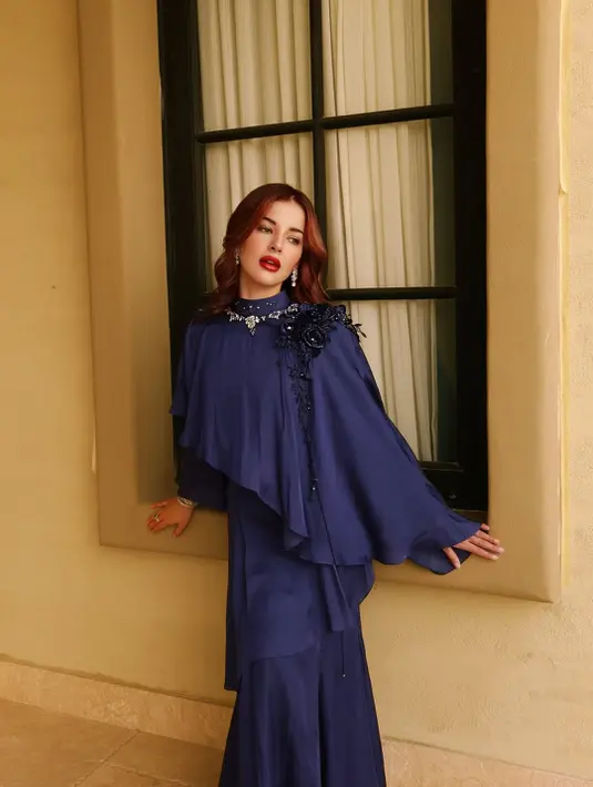 Ia terlihat mengenakan busana slim sillhouette dan kerah bulat tinggi dari Dyah Ayu Andari. Busana berpotongan ruffle ini dilengkapi dengan aksen bunga di pundak.