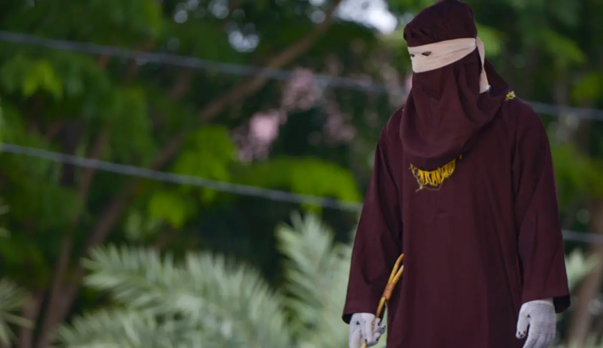 Seorang anggota polisi Syariah bersiap melakukan hukuman cambuk kepada seorang pria di Banda Aceh, Senin (21/10/2019). Empat sopir dikenakan 6 kali sabetan cambuk setelah dipotong masa tahanan dua kali cambuk karena terbukti melakukan perbuatan maisir (judi). (CHAIDEER MAHYUDDIN / AFP)
