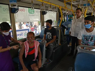 Seorang petugas kesehatan menyuntik pekerja dengan vaksin Covid-19 Covishield di dalam bus penumpang yang diubah menjadi pusat vaksinasi keliling di Kolkata, Kamis (3/6/2021). India telah menderita pandemi yang menghancurkan sejak April, dan baru-baru ini mulai mereda. (Dibyangshu SARKAR/AFP)