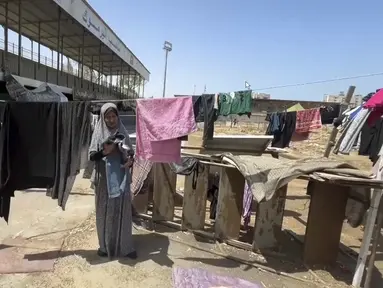 Gambar dari video ini memperlihatkan seorang perempuan menjemur pakaian di Stadion Olahraga Yarmouk, Kota Gaza, Jalur Gaza, Jumat 5 Juli 2024. (AP Photo)