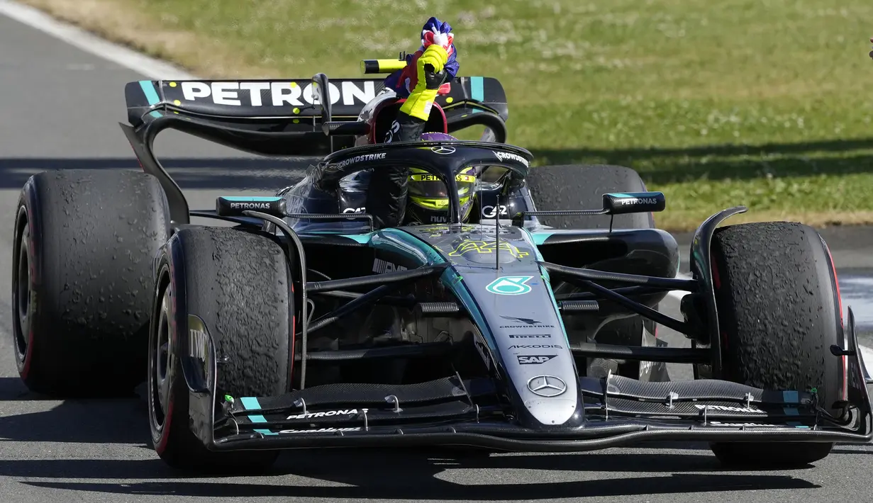Pembalap Mercedes, Lewis Hamilton memegang bendera Inggris saat melakukan victory lap pada Formula 1 GP Inggris 2024 yang berlangsung di Sirkuit Silverstone, Inggris, Minggu (08/07/2024). (AFP/Luca Bruno)