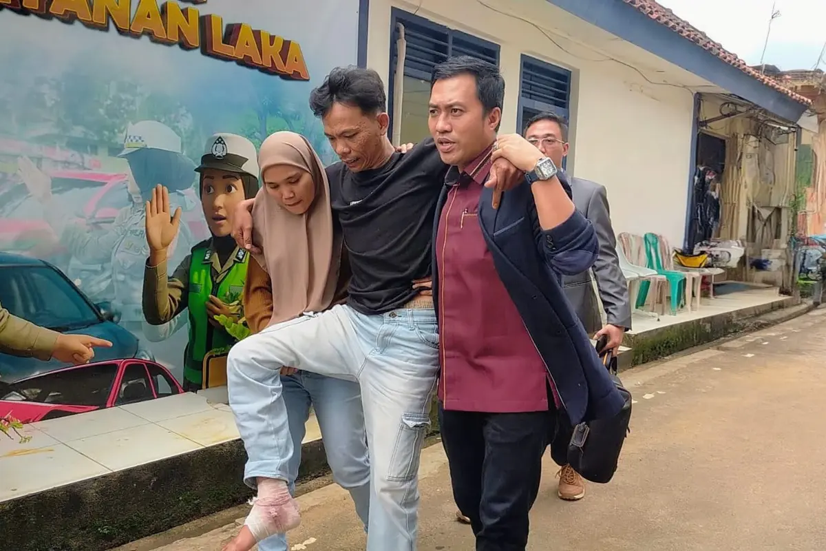 Dika Sanjaya, driver ojek online yang menjadi korban tabrak lari harus dibopong oleh istrinya ketika membuat laporan ke Polresta Bandar Lampung (Liputan6.com/Ardi Munthe)