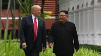 Keakraban Presiden AS Donald Trump (kiri) dengan Pemimpin Korea Utara Kim Jong-un saat berjalan di taman Hotel Capella, Pulau Sentosa, Singapura, Selasa (12/6). Trump dan Kim bertemu untuk membicarakan upaya denuklirisasi Korut. (Anthony Wallace/Pool/AFP)